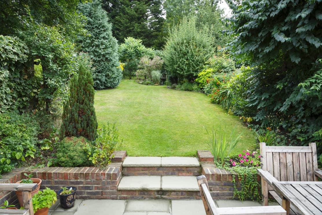 Terraced and landscaped back garden in England UK with patio, grass and stone steps