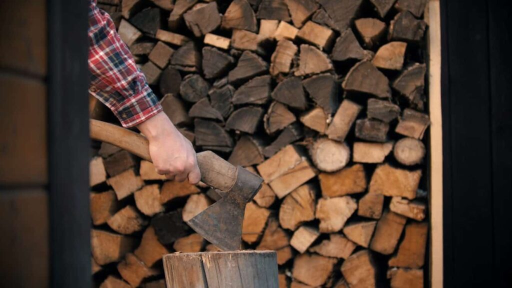 Chopping wood with an axe in woodpile. Mid shot