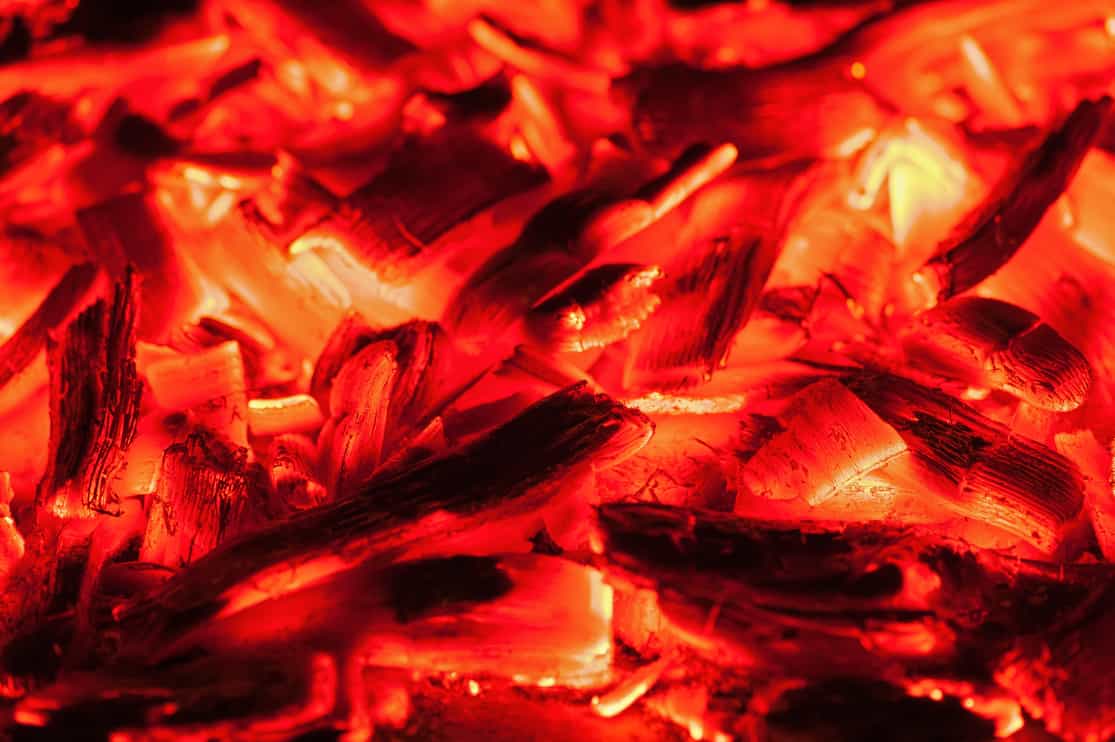 Open fire in fireplace. Closeup of burning stack of firewood with orange flames.